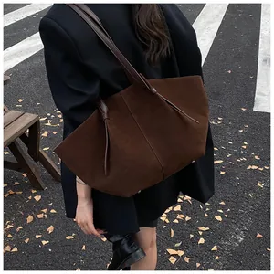 Détail d'un grand cabas en daim marron avec lanières en cuir pour le quotidien