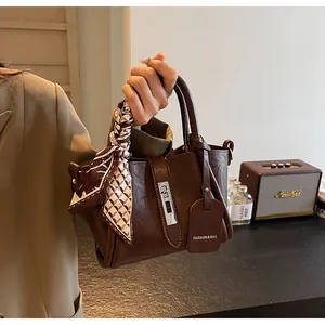 Detail of dark brown leather bucket bag with silver lock and decorative silk scarf