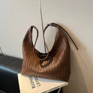 Close-up of brown woven leather texture on a hobo shoulder bag with silver buckle