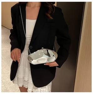 Dettaglio di una pochette in acrilico argento specchiato con catena in metallo su abito nero