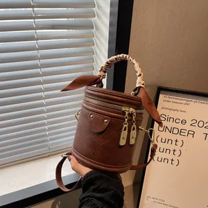 Detail of vintage brown bucket bag with cow print scarf handle and gold zippers