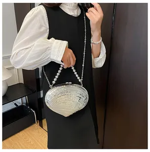 Détail du sac de soirée argenté en forme de coquillage avec poignée perlée et chaîne