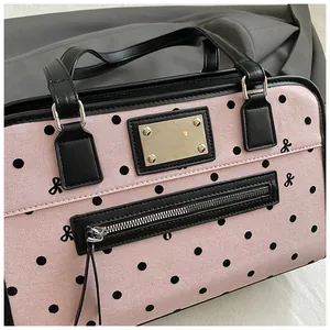 Gros plan du sac à main rose à pois avec motifs de nœuds et bordures en cuir noir raffiné
