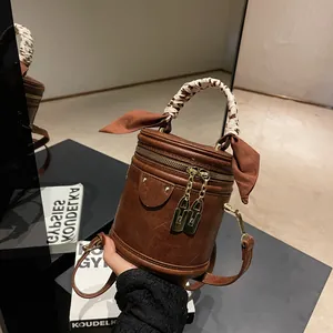 Detail view of brown leather bucket bag with leopard scarf and golden hardware