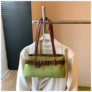 Détail d'un sac cabas en daim vert avec ceinture en cuir marron et boucle en métal