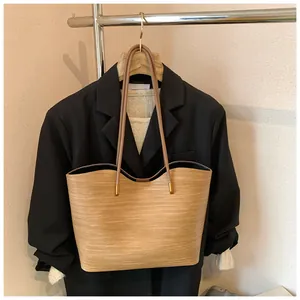 Detail of light brown woven tote bag featuring a scalloped rim and gold metal hardware