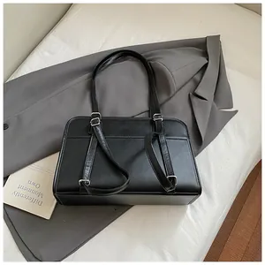 Détail du sac à bandoulière minimaliste en similicuir noir avec doubles anses et coutures