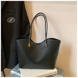 Detailed close-up of black woven texture tote bag with elegant gold metal hardware