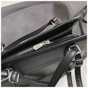 Gros plan d'un sac cabas noir en cuir synthétique avec fermeture éclair argentée et boucles