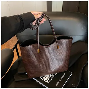 Detailed view of dark brown woven tote bag with slim handles and gold metal hardware