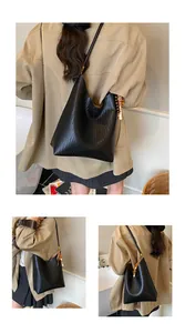 Détail d'un sac cabas noir tressé en cuir synthétique de qualité avec breloque perlée