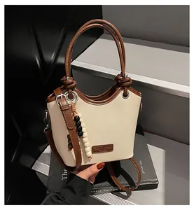 Détail du sac seau en toile avec bordure en cuir marron et pendentif décoratif en perles