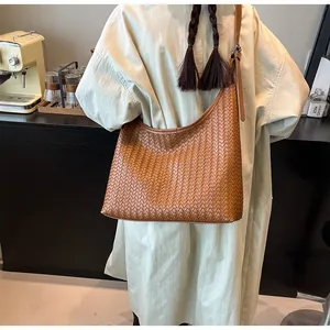 Brown woven hobo shoulder bag with large capacity and adjustable strap on a model