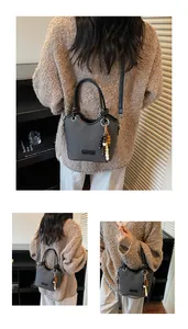 Détails du sac seau en cuir gris avec breloque perlée et bandoulière réglable