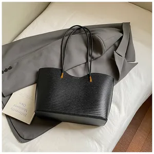 Close-up of black woven texture tote bag with fine stitching and gold hardware detail