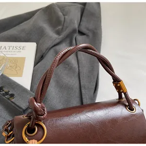 Detail of twisted leather handle and gold metal rings on a vintage brown handbag