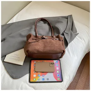 Details der Vintage-Tragetasche in Dunkelbraun auf grauem Sakko mit Tablet