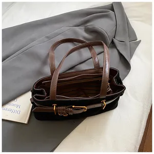 Détail du sac cabas en daim noir avec anses en cuir marron et doublure rayée chic