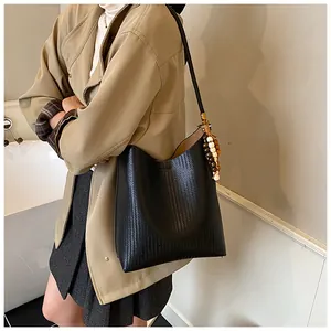 Détail d'un sac hobo en cuir tressé noir avec pampille perlée décorative