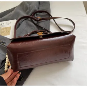 Detail shot of vintage dark brown faux leather bag with elegant gold twist lock closure