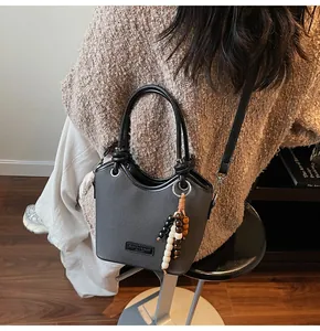 Détail d'un sac seau gris avec cuir grainé et pendentif de perles décoratives