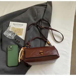 Close-up of dark brown glossy leather handbag with gold twist lock and beaded charm