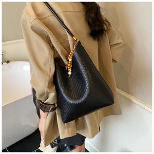 Gros plan d'un cabas tressé noir avec pendentif en perles de bois et boucles dorées