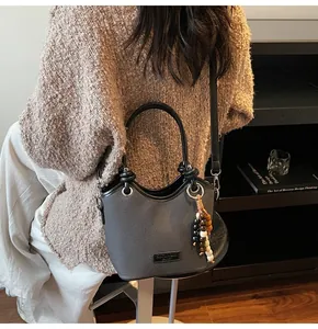 Détail du sac seau gris avec cuir texturé et breloque en perles de bois tricolores