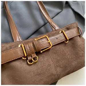 Détail du sac cabas en daim marron foncé avec boucle de ceinture et anneaux dorés mats