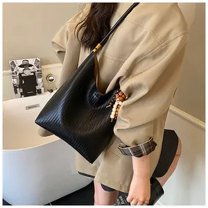 Gros plan d'un sac hobo en cuir tressé noir avec breloques perlées sur un mannequin