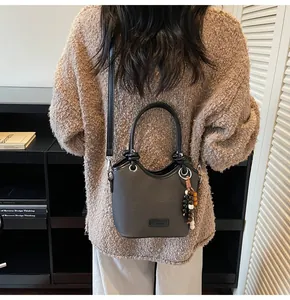 Détail d'un sac seau en cuir gris foncé avec un accessoire de breloque en perles colorées