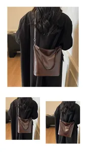 Détail de la texture cuir marron foncé brillant et du lettrage imprimé sur le sac fourre-tout