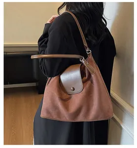 Detail of a large brown suede tote bag featuring a leather strap and flap closure