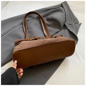 Détails des coutures en daim marron et de la boucle métallique sur le sac fourre-tout