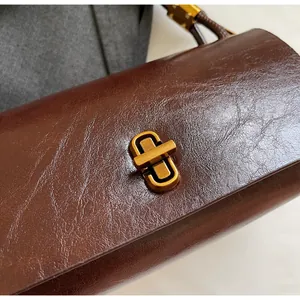 Detailed macro view of dark brown oil-wax leather texture and matte gold metal twist lock