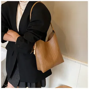Sac cabas en cuir tressé marron avec pompon en perles de bois dans un cadre de mode