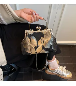 Détail de la broderie florale, fermoir perle et poignée en métal du sac de soirée