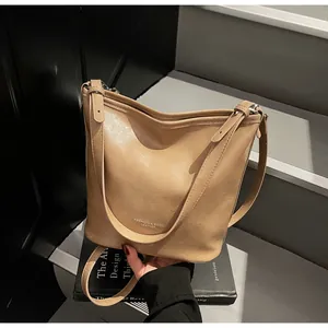 Détail du sac seau en cuir kaki avec lettrage embossé sur un escalier minimaliste