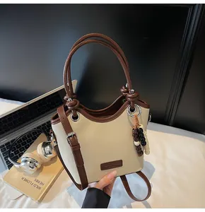 Détail du sac seau en toile avec finitions en cuir et breloque en perles de bois