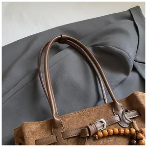 Detail der Vintage-Matte-Tasche mit brauner Wildleder-Textur und Holzperlen-Anhänger