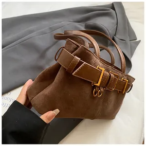 Détail du sac seau en daim marron foncé avec ceinture en cuir et boucle dorée