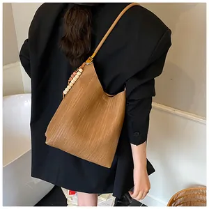 Vue détaillée du sac porté épaule marron tressé avec bandoulière perlée sur mannequin