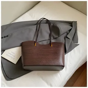 Detailed close-up of dark brown woven tote bag texture with fine golden metal hardware