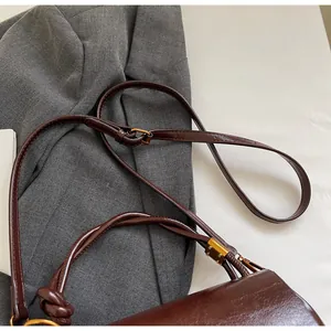Detailed close-up of dark brown leather shoulder strap with gold buckle and adjustable design