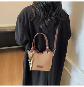 Vue détaillée du sac seau kaki avec perles en bois et écusson en cuir au style rétro