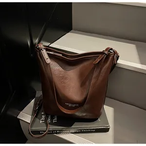 Gros plan sur la texture du cuir marron foncé et l'imprimé blanc sur le sac hobo