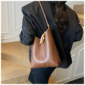 Gros plan d'un sac à bandoulière marron tressé avec pendentif en perles de bois