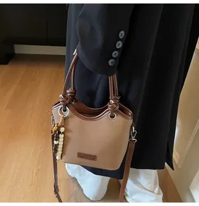 Détail du sac seau en toile avec finitions en cuir et breloque perlée sur mannequin