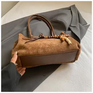Detailansicht der braunen Wildledertasche mit Lederriemen und Holzperlenanhänger
