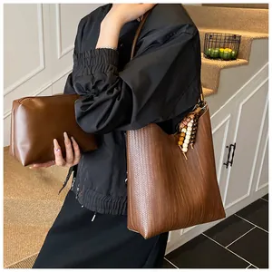 Détail du sac bandoulière marron à texture tressée avec pochette assortie et pompon